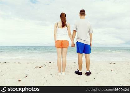 Young couple looking thoughtful while standing next to each other on beach. Young couple looking thoughtful while standing next to each other on beach in sports wear