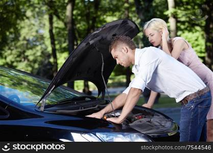 Young Couple looking under the hood of car