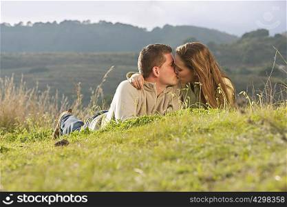 Young couple lying and kissing in field