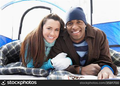 Young couple lying in sleeping bags in tent portrait.