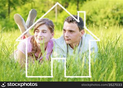 Young couple lying on grass dreaming to a house