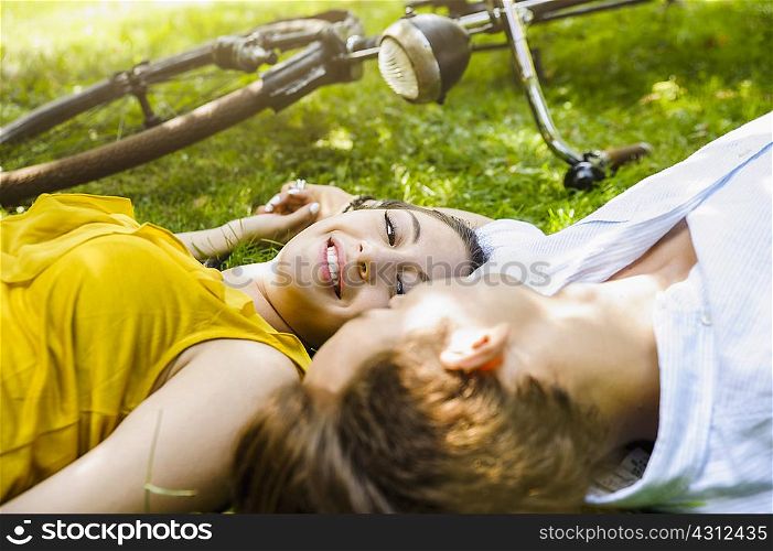 Young couple lying on grass holding hands