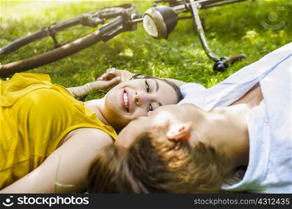 Young couple lying on grass holding hands