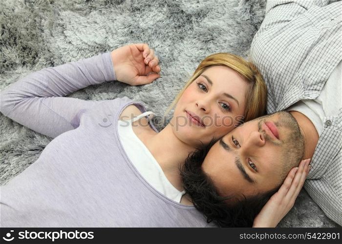 Young couple lying on grey carpet