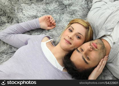 Young couple lying on grey carpet