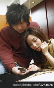 Young couple lying on the bed holding a mobile phone