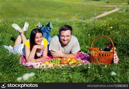 Young couple lying on the blanket during picnic on the meadow. Couple on the picnic