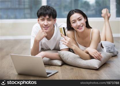 Young couple lying on the floor and using a digital tablet to shop online
