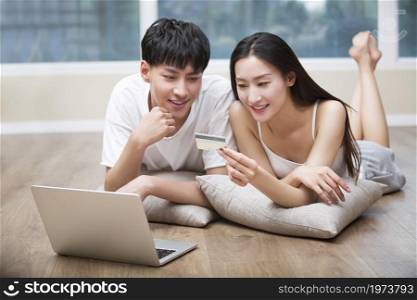 Young couple lying on the floor and using a digital tablet to shop online