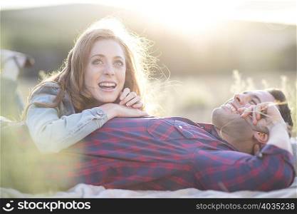 Young couple lying together chewing straw grass