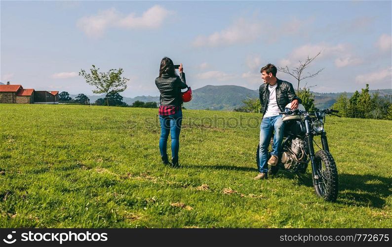 Young couple making a landscape photo during a stop of a motorcycle trip. Couple making a landscape photo during a motorcycle trip