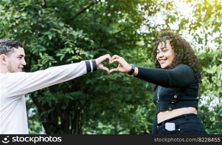 Young couple making heart shape with hands, Happy couple making heart shape with hands, Two friends outdoors making heart shape with hands