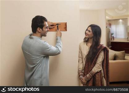 Young couple newlywed in traditional dress placing name plate to home