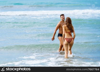 Young couple of beautiful athletic bodies bathing together on the beach enjoying their holiday at sea. Young couple bathing together on the beach enjoying their holiday at sea