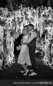 young couple of newlyweds on the evening illuminated arch