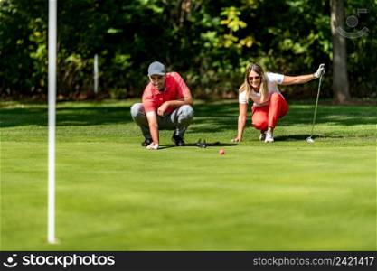 Young couple on a golf course, reading green