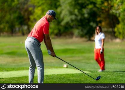 Young couple on a golfing vacation, man teeing off