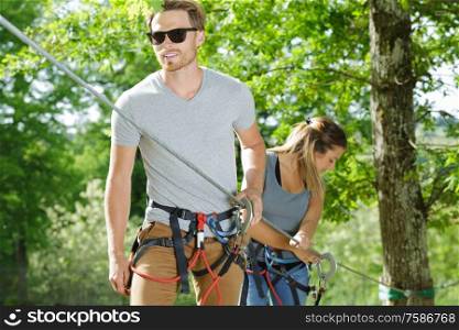 young couple on adventure park course through the trees