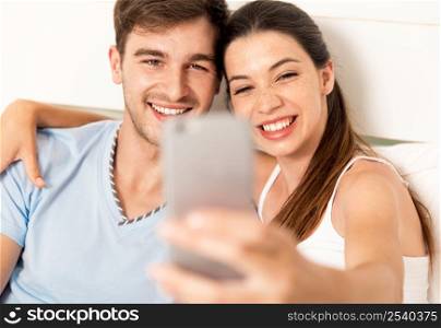 Young couple on bed making selfies with a phone