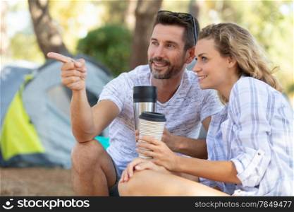 young couple on camping by the river drinking coffee