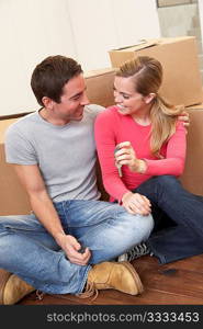 Young couple on moving day sitting with cardboard boxes