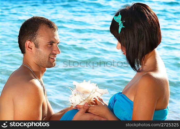 Young couple on the beach with seashell