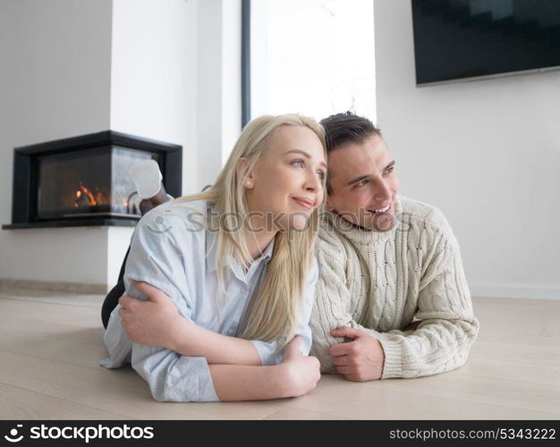 Young Couple on the floor in front of fireplace surfing internet using digital tablet on cold winter day