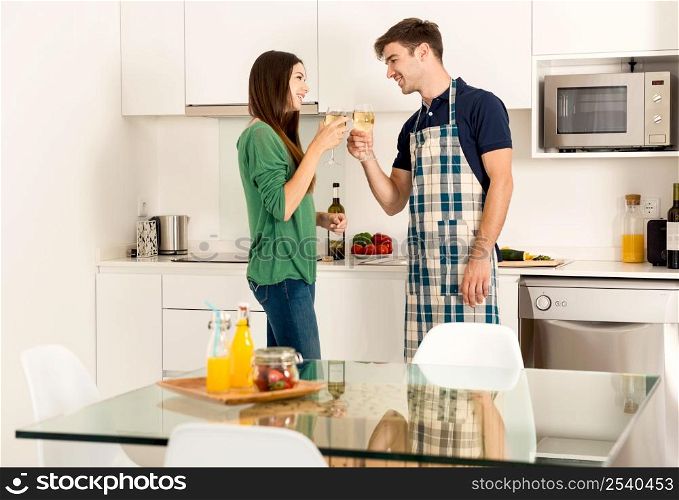Young couple on the kitchen enjoying a glass of white wine