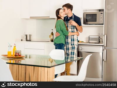 Young couple on the kitchen enjoying a glass of white wine