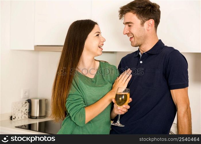 Young couple on the kitchen enjoying a glass of white wine