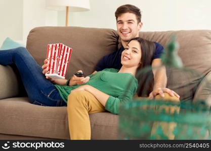 Young couple on the sofa and eating popcorns