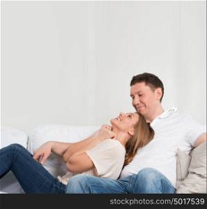 Young couple on the sofa in love planning future and having fun. Lots of copyspace