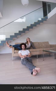 Young couple on the sofa watching television together in their luxury home