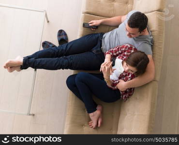 Young couple on the sofa watching television together in their luxury home