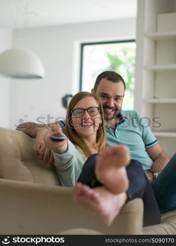 Young couple on the sofa watching television together in their luxury home