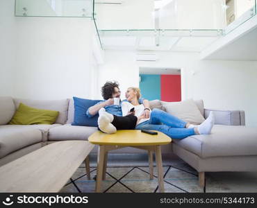 Young couple on the sofa watching television together in their luxury home