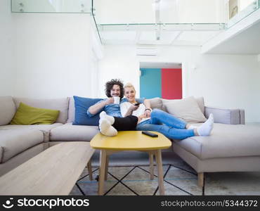 Young couple on the sofa watching television together in their luxury home