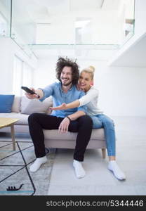 Young couple on the sofa watching television together in their luxury home