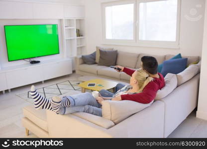 Young couple on the sofa watching television together in their luxury home