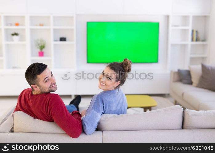 Young couple on the sofa watching television together in their luxury home