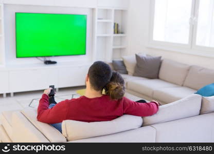 Young couple on the sofa watching television together in their luxury home