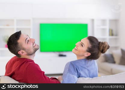 Young couple on the sofa watching television together in their luxury home