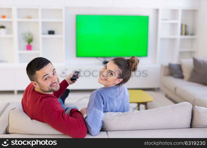 Young couple on the sofa watching television together in their luxury home