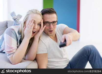 Young couple on the sofa watching television together in their luxury home