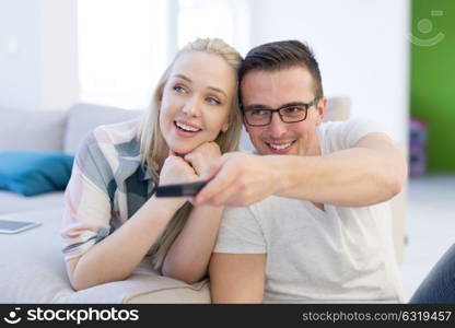 Young couple on the sofa watching television together in their luxury home