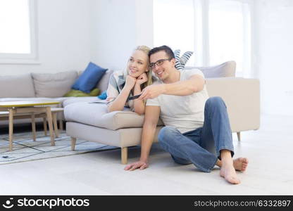 Young couple on the sofa watching television together in their luxury home