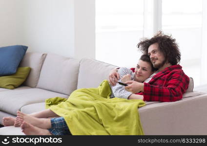 Young couple on the sofa watching television together in their luxury home