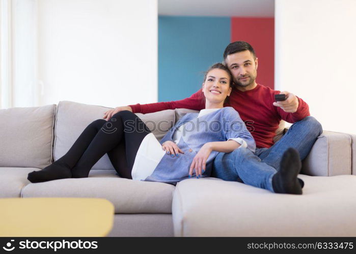 Young couple on the sofa watching television together in their luxury home