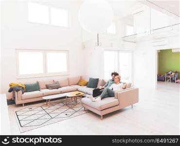 Young couple on the sofa watching television together in their luxury home. Young couple on the sofa watching television
