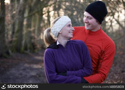 Young Couple On Winter Run Through Woodland